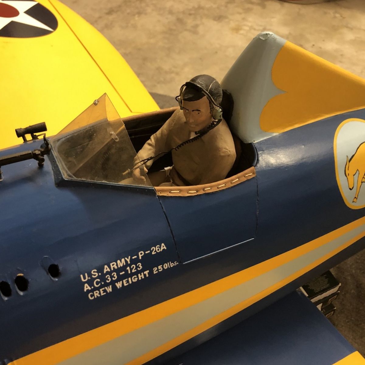 The pilot inside a remote control Boeing P-26 Peashooter airplane outfitted with Hitec servomotors, a signal reversing switch, and a Futaba R617FS 2.4 GHz reciever.